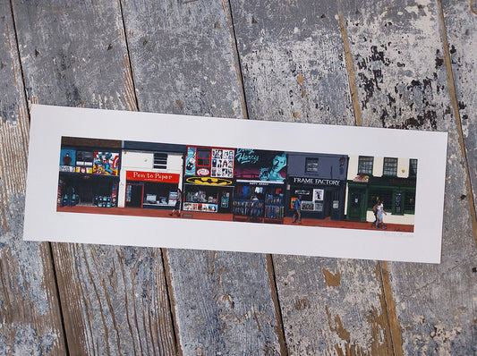 Panoramic print of a street scene in brighton with various shops on a wooden surface