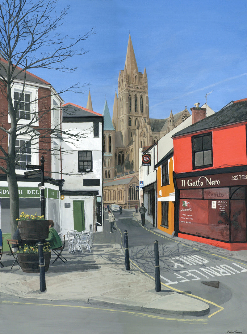 Painting of a street scene in Truro by Martin Thomas with colorful buildings and a cathedral spire under a blue sky.