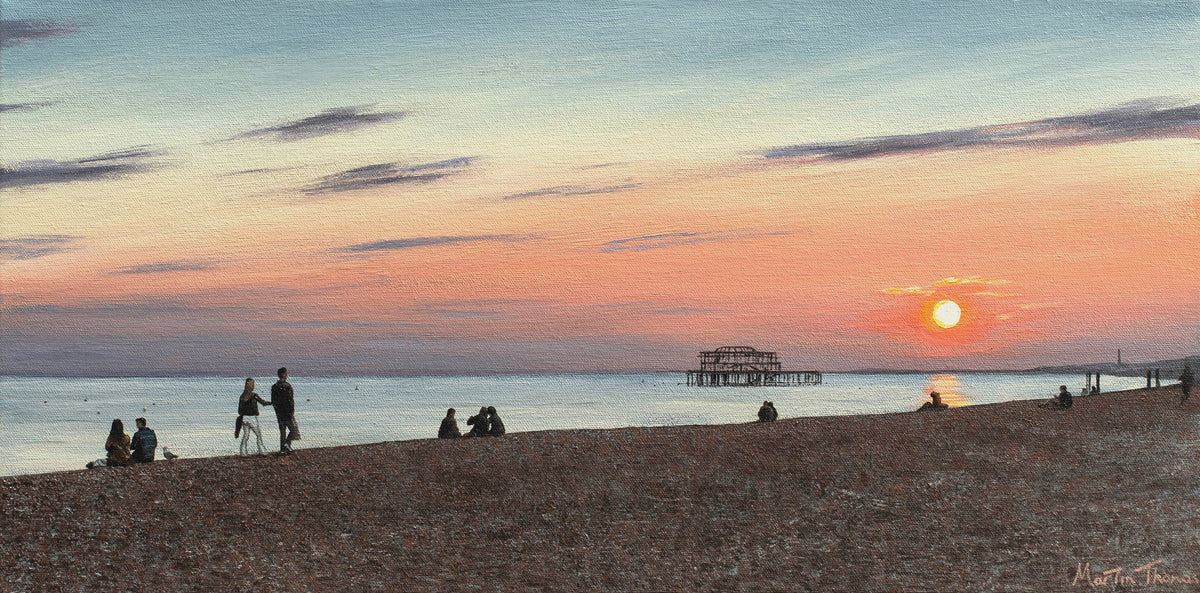 Painting by Martin Thomas of a Sunset over Brighton beach with people sitting on the sand and the West pier in the distance.