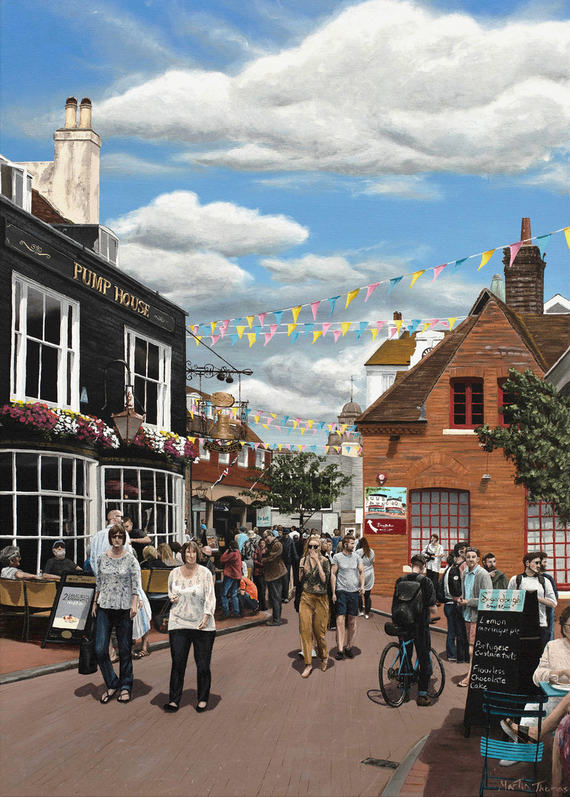 Brighton street scene Painted by Martin Thomas with people, shops, and colorful flags under a blue sky.